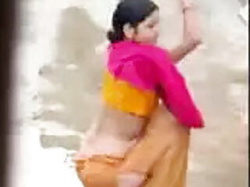 Bhabhi bathes in the open air, secretly captured by a neighbor