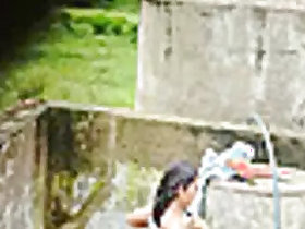 Indian Village Girl bathing near an outdoor water tank